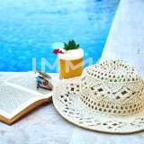 Symbolfoto Buch und Hut am Pool
